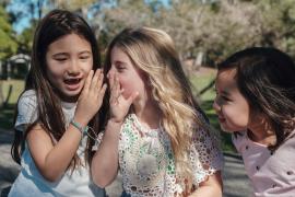 young child whispering into another child's ear