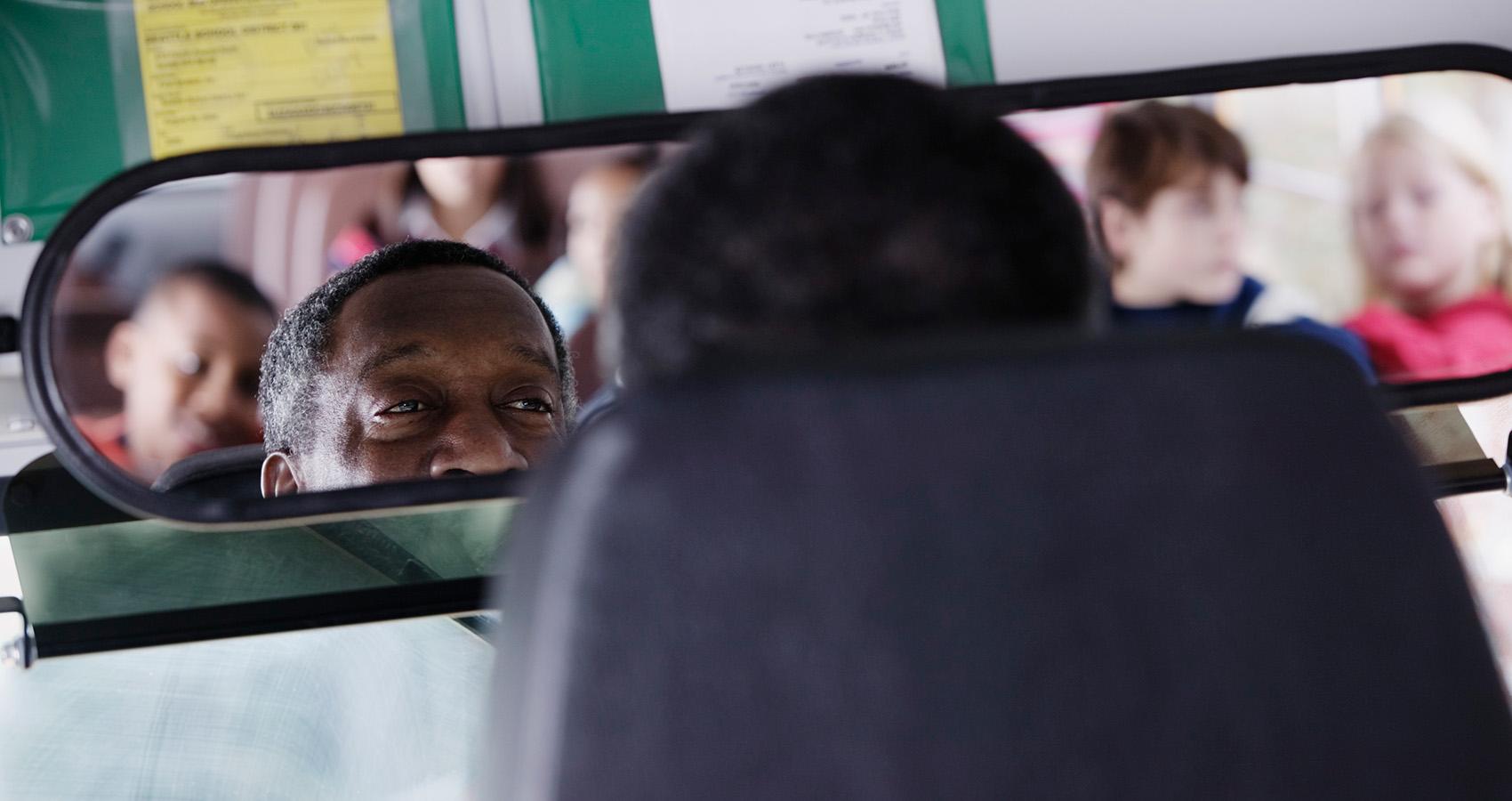 Bus driver looking at kids in rear-view mirror